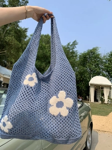 Detail der blauen Häkeltasche mit weißem Blumenmuster und Baumwollstrickstruktur