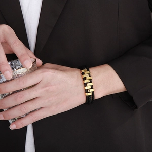Detail of men's multi-layer woven leather bracelet in black and gold on a model's wrist