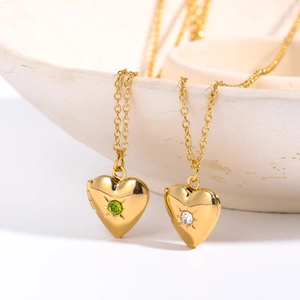 Close-up of gold heart locket necklaces with starburst gemstones on ceramic dish