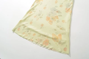 Vue détaillée du tissu floral léger jaune pâle avec motifs de fleurs orange et gris