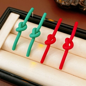 Detail view of green and red knotted stud earrings displayed inside a black jewelry box