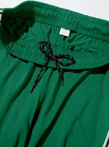 Detail of green sports joggers featuring elastic waistband with black and white drawstring