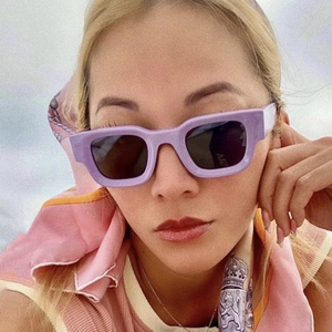 Close-up of a trendy celebrity wearing retro purple square frame sunglasses with dark lenses