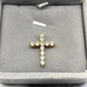 Close-up of gold-plated cross pendant with white zircons in a gray velvet jewelry box
