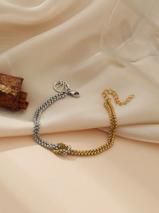 Detail of two-tone gold and silver chain bracelet with knot design and peace sign tag