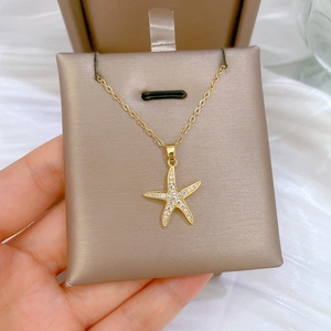 Close-up of sparkling gold starfish pendant with cubic zirconia on beige jewelry card