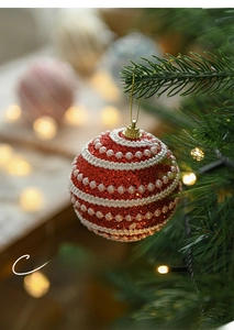 Close-up of red Christmas ball with white wave texture and pearl accents on tree