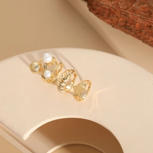 Detailed view of 14K gold plated rings set with pearls and star motif on ceramic stand
