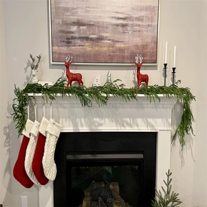 Christmas fireplace decor with green pine garland, knit stockings and deer figurines