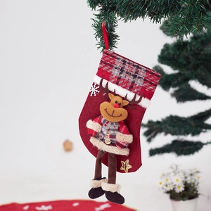 Close-up of red Christmas stocking with 3D plush reindeer hanging on a tree branch