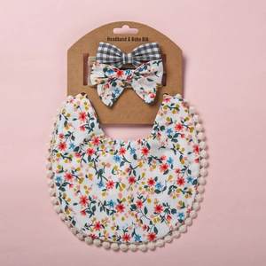 Détail d'un bavoir floral pour bébé et de bandeaux à nœuds assortis sur support