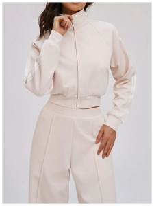 Detail view of pink tracksuit sleeve showing three white athletic stripes and ribbed cuffs