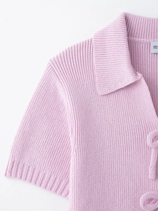Detailed close-up of light pink knit polo top with ribbed texture and collar
