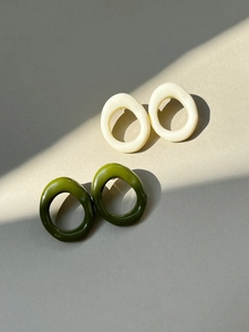 Detail view of oval resin earrings in cream and olive green with elegant shadows