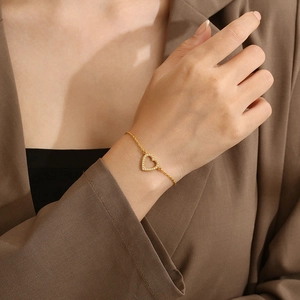 Bracelet cœur doré élégant serti de cristaux étincelants porté au poignet d'une femme