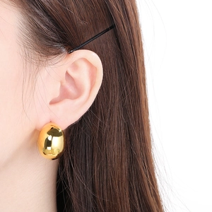 Gros plan d'une boucle d'oreille en acier inoxydable doré 18 carats en forme de galet