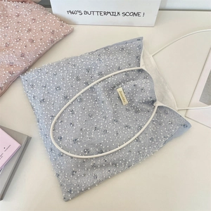 Close-up of light blue tote bag featuring delicate white lace mesh and pearl embellishments