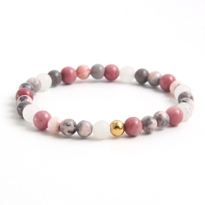 Pink rhodochrosite beaded bracelet with elegant gold accent bead on white background