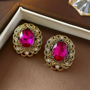 Detailed macro view of vintage gold earrings with pink oval stones and diamond flower patterns