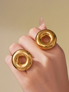 Detailed close-up of two thick chunky hollow gold rings worn on fingers with a glossy finish