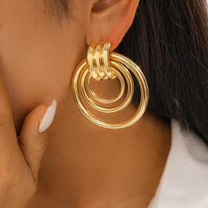 Close-up of model wearing chunky layered geometric gold hoop earrings with polished finish