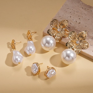 Detail view of the elegant pearl and gold floral earring set displayed on a stone pedestal