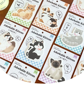 Close-up of adorable cat-shaped sticky notes with various breeds and plaid background