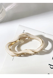 Close-up of elegant cream resin hair claw clip with gold metal irregular wavy design