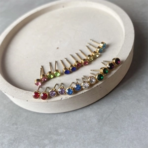Detailed arrangement of colorful birthstone stud earrings on a textured stone tray