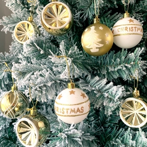 Detail of white and gold Christmas balls with festive patterns on a snowy pine tree