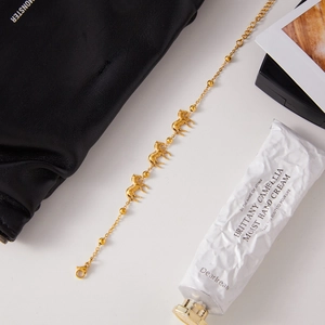 Detailed shot of gold horse charm bracelet with beads and lobster clasp on neutral background