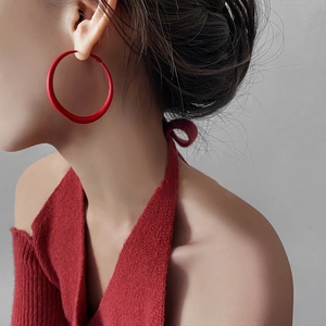 Close-up of matte red oversized hoop earrings worn by a model for a chic retro look