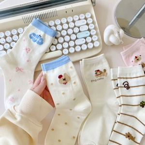 Cartoon crew socks with bow, polka dots, and dog patterns in a creative flat lay display