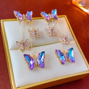 Elegant gold butterfly tassel earrings with purple and blue crystals in a gift box