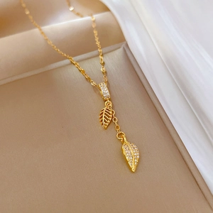 Close-up of gold titanium steel necklace featuring detailed zircon-encrusted leaf pendants