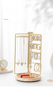 Detail of a rotating gold metal jewelry rack with wooden base and necklace hooks