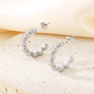 Vue détaillée de boucles d'oreilles argentées en C avec texture rayée et perles blanches