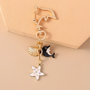 Detail of a gold dolphin keychain with black enamel dolphin, shell, and starfish charms