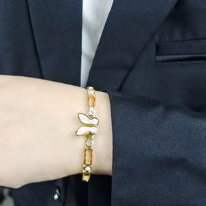 Close-up of a gold butterfly bracelet with white shell inlay and zircon accents