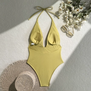 Flat lay of olive green one-piece swimsuit with straw hat and sunglasses decor