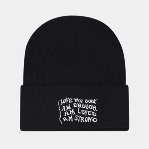 Close-up of black knit beanie with white embroidered mental health positive slogans