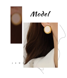Detail shot of a model wearing retro cream round geometric earrings with gold trim
