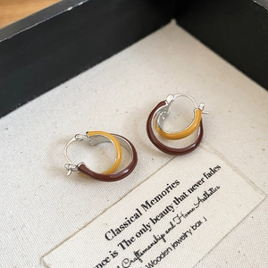 Detail macro shot of vintage crossover hoop earrings in ginger and dark coffee enamel