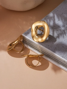 Three chunky gold irregular lava rings displayed on a vintage book with natural shadows
