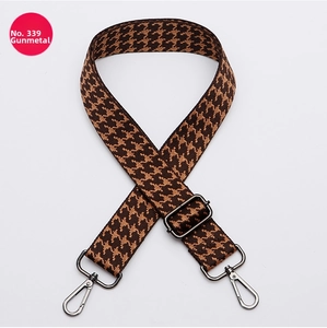 Detail of wide adjustable crossbody bag strap with brown houndstooth pattern and gunmetal hooks