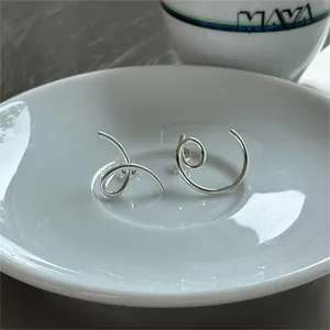 Macro shot of silver spiral 925 sterling silver earrings on a white porcelain plate