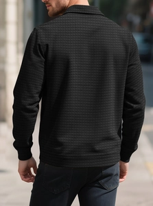 Macro detail of men's black knit shirt featuring a textured jacquard checkerboard pattern