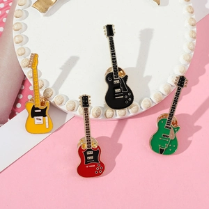 Close-up of four colorful guitar enamel pins in yellow red black and emerald green