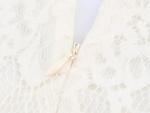 Nahaufnahme der eleganten cremeweißen Spitze und des verdeckten Reißverschlusses am Kleid
