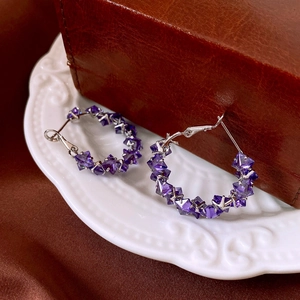 Detail of purple faceted crystal bead hoop earrings with silver clasps on a vintage tray